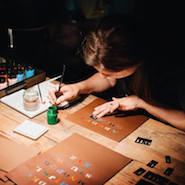 Burberry craftswoman customizing merchandise with hand painted monogramming