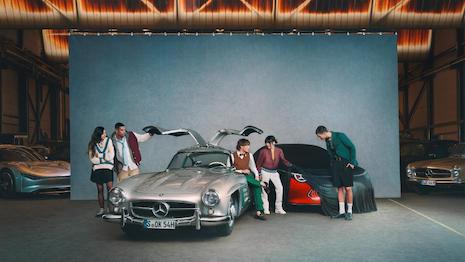 A group of students surround famous Mercedes-Benz models in the new initiative. Image credit: Mercedes-Benz